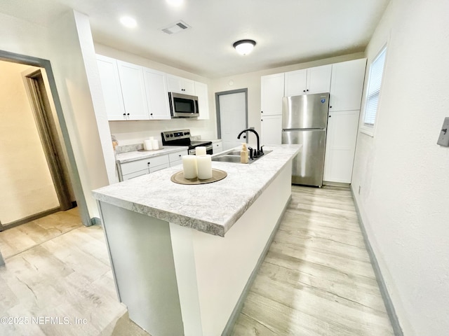 7381 Fernandina Ave, Jacksonville, FL 32208 - kitchen with appliances with stainless steel finishes, a sink, light wood-type flooring, white cabinets, and baseboards