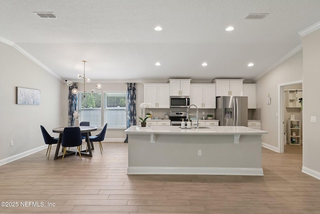 2623 Cold Stream Ln, Green Cove Springs, FL 32043 - kitchen featuring appliances with stainless steel finishes, ornamental molding, a sink, a center island with sink, and light wood finished floors