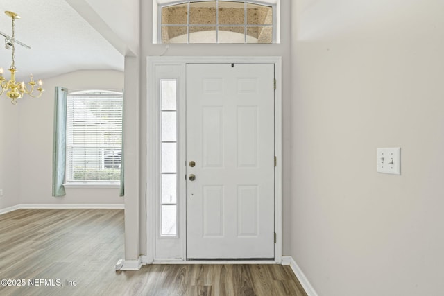 1608 Rustling Dr, Fleming Island, FL 32003 - entryway with a chandelier, wood finished floors, baseboards, and vaulted ceiling