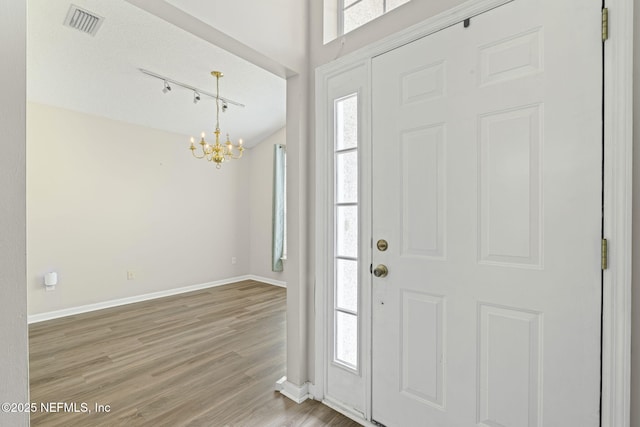 1608 Rustling Dr, Fleming Island, FL 32003 - foyer with a chandelier, wood finished floors, baseboards, and rail lighting