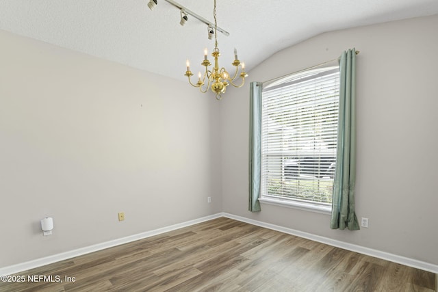 1608 Rustling Dr, Fleming Island, FL 32003 - empty room featuring a chandelier, vaulted ceiling, wood finished floors, baseboards, and a textured ceiling
