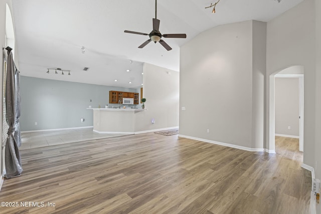 1608 Rustling Dr, Fleming Island, FL 32003 - unfurnished living room featuring arched walkways, a ceiling fan, light wood-style floors, vaulted ceiling, and baseboards