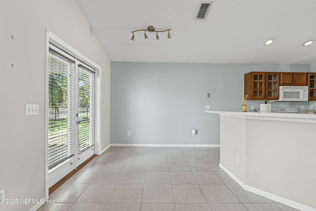 1608 Rustling Dr, Fleming Island, FL 32003 - kitchen featuring white microwave, brown cabinets, glass insert cabinets, light countertops, and light tile patterned floors