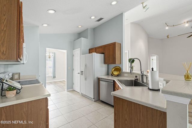 1608 Rustling Dr, Fleming Island, FL 32003 - kitchen with white appliances, a sink, vaulted ceiling, a peninsula, and brown cabinets