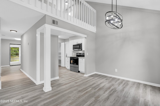 8687 Bishopswood Dr, Jacksonville, FL 32244 - unfurnished living room with light wood-style floors, a chandelier, and a towering ceiling