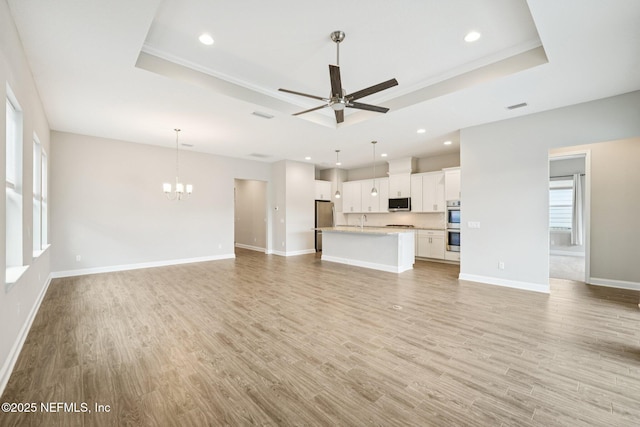 68 Briar Ridge Ct, Ponte Vedra, FL 32081 - unfurnished living room featuring a raised ceiling, ceiling fan, a chandelier, light wood-style floors, and recessed lighting