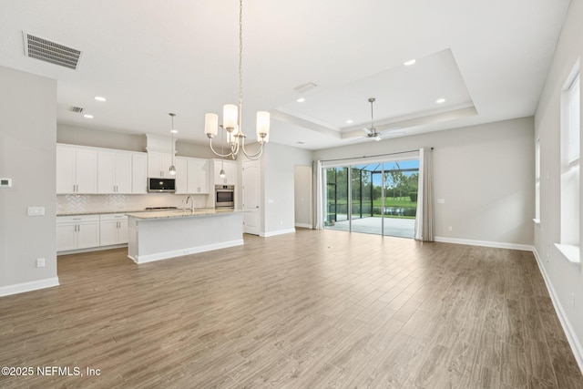 68 Briar Ridge Ct, Ponte Vedra, FL 32081 - unfurnished living room with a raised ceiling, light wood-style flooring, recessed lighting, ceiling fan, and a chandelier
