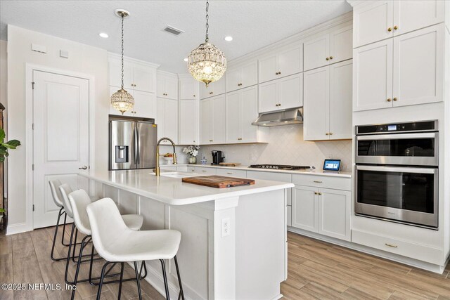37 Permit Ct, Saint Augustine, FL 32092 - kitchen with stainless steel appliances, under cabinet range hood, light wood finished floors, recessed lighting, and a breakfast bar area