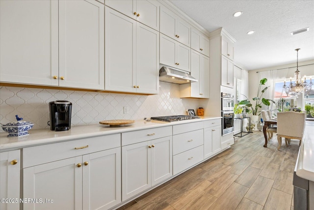 37 Permit Ct, Saint Augustine, FL 32092 - kitchen featuring under cabinet range hood, appliances with stainless steel finishes, light countertops, white cabinetry, and a textured ceiling