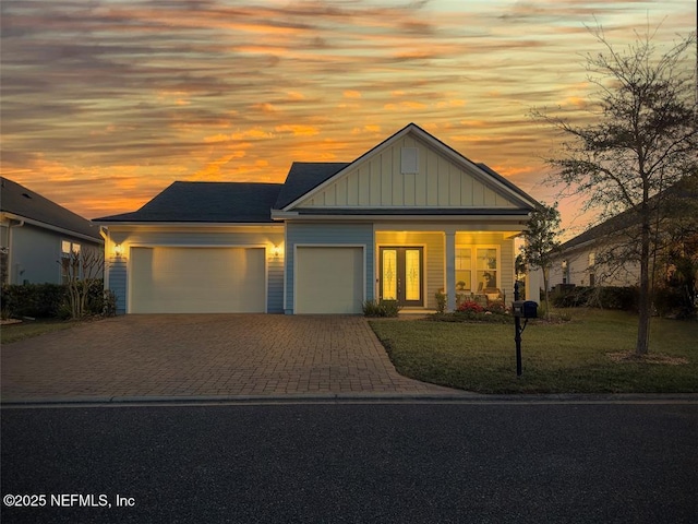 95191 Poplar Way, Fernandina Beach, FL 32034 - view of front facade featuring a garage, board and batten siding, decorative driveway, a front yard, and a porch
