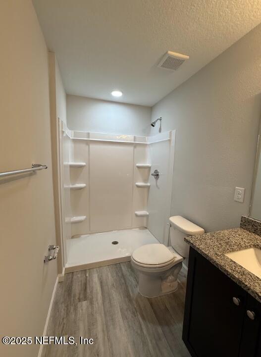 8051 Driggers St, Jacksonville, FL 32220 - bathroom with wood finished floors, vanity, a shower, toilet, and a textured ceiling