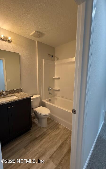 8051 Driggers St, Jacksonville, FL 32220 - bathroom featuring a textured ceiling, toilet, vanity, wood finished floors, and shower / tub combination