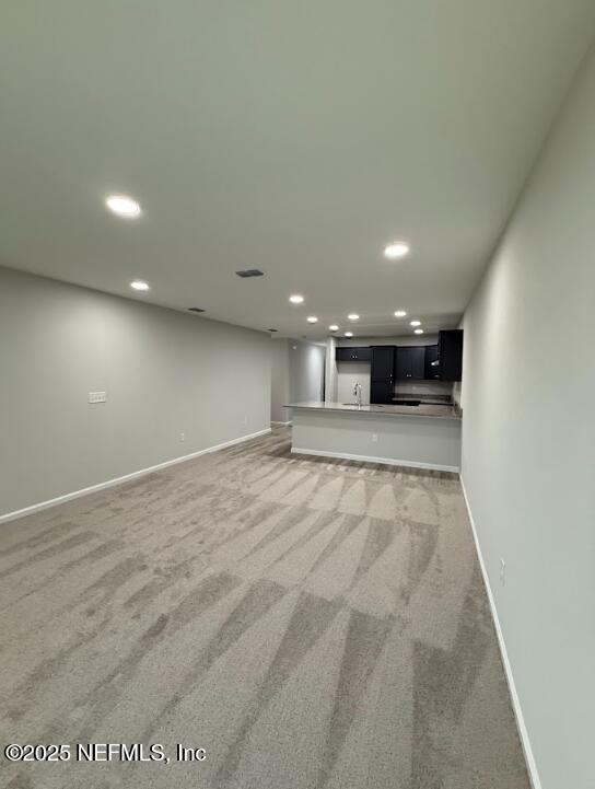 8051 Driggers St, Jacksonville, FL 32220 - unfurnished living room with light colored carpet, recessed lighting, baseboards, and bar