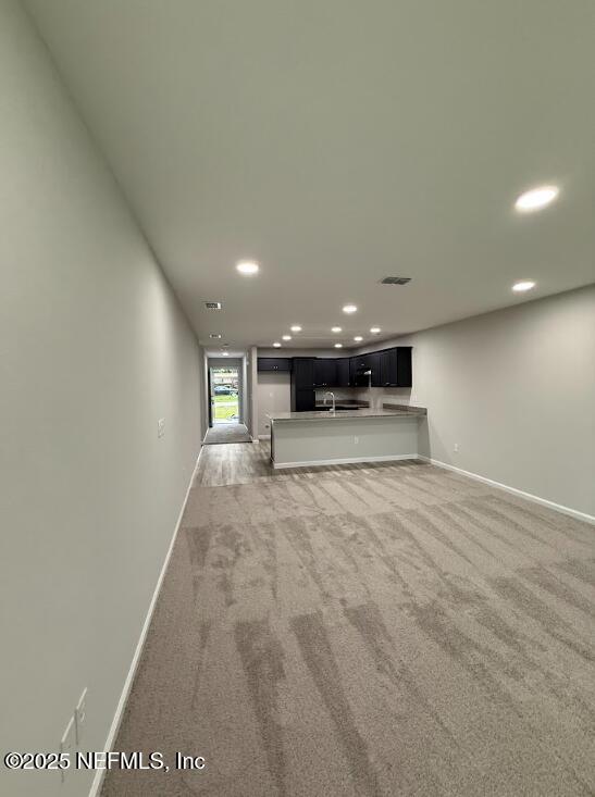 8051 Driggers St, Jacksonville, FL 32220 - unfurnished living room with light carpet, baseboards, recessed lighting, and a sink