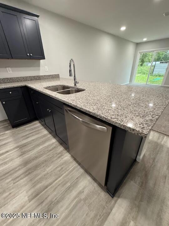 8051 Driggers St, Jacksonville, FL 32220 - kitchen with a sink, stainless steel dishwasher, light wood-style floors, a peninsula, and light stone counters