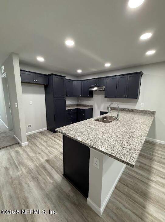 8051 Driggers St, Jacksonville, FL 32220 - kitchen featuring a sink, a peninsula, baseboards, light stone counters, and under cabinet range hood