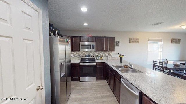 1318 Lake Shore Blvd, Jacksonville, FL 32205 - kitchen featuring appliances with stainless steel finishes, a sink, light wood-style floors, light countertops, and a textured ceiling