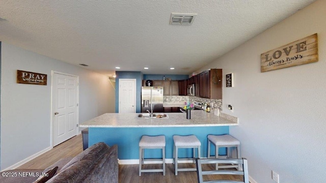 1318 Lake Shore Blvd, Jacksonville, FL 32205 - kitchen with appliances with stainless steel finishes, a peninsula, tasteful backsplash, wood finished floors, and a kitchen breakfast bar