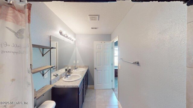 1318 Lake Shore Blvd, Jacksonville, FL 32205 - bathroom featuring a textured wall, double vanity, tile patterned flooring, a textured ceiling, and baseboards