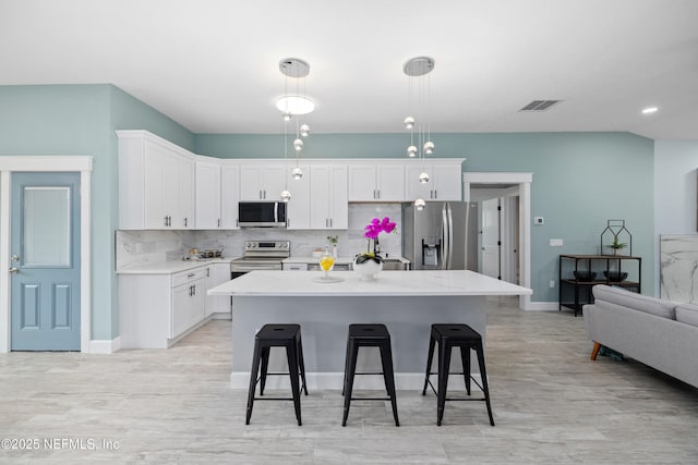3064 Hickory Glen Dr, Jacksonville, FL 32065 - kitchen featuring stainless steel appliances, a breakfast bar area, white cabinets, and tasteful backsplash