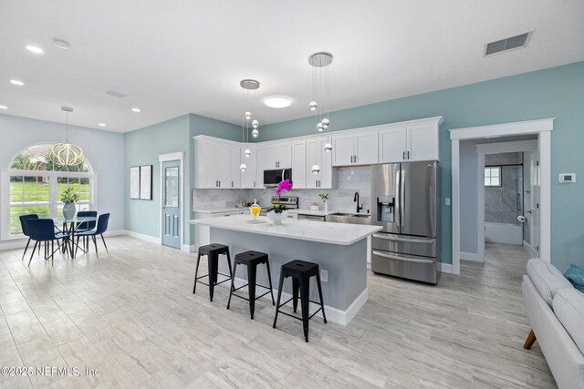 3064 Hickory Glen Dr, Jacksonville, FL 32065 - kitchen with stainless steel appliances, light countertops, white cabinets, a kitchen island, and a breakfast bar area