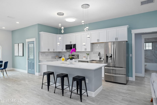 3064 Hickory Glen Dr, Jacksonville, FL 32065 - kitchen featuring stainless steel appliances, a sink, a kitchen bar, light countertops, and baseboards
