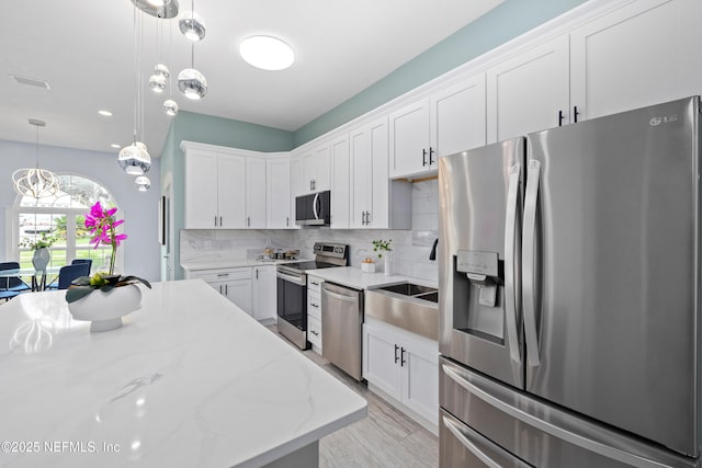 3064 Hickory Glen Dr, Jacksonville, FL 32065 - kitchen with appliances with stainless steel finishes, white cabinets, backsplash, hanging light fixtures, and light stone countertops