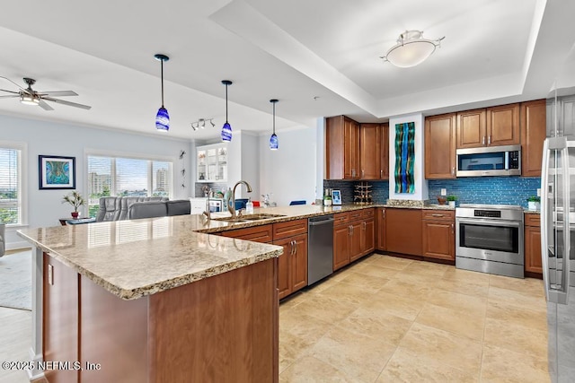 525 3rd St S Unit 513, Jacksonville Beach, FL 32250 - kitchen with appliances with stainless steel finishes, a peninsula, decorative backsplash, a tray ceiling, and brown cabinets
