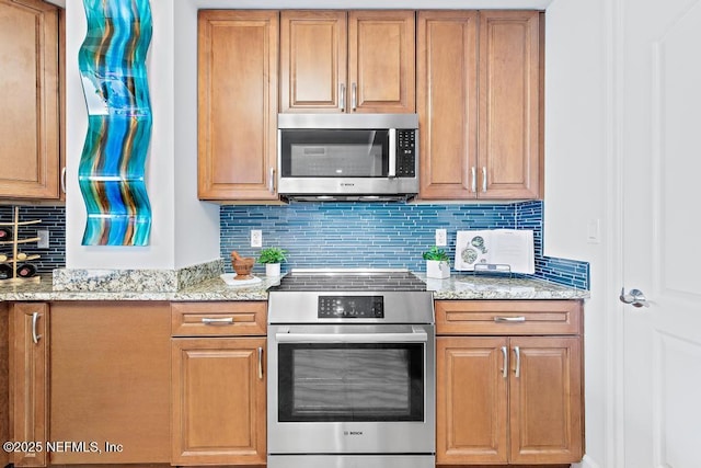 525 3rd St S Unit 513, Jacksonville Beach, FL 32250 - kitchen with appliances with stainless steel finishes, tasteful backsplash, light stone counters, and brown cabinetry