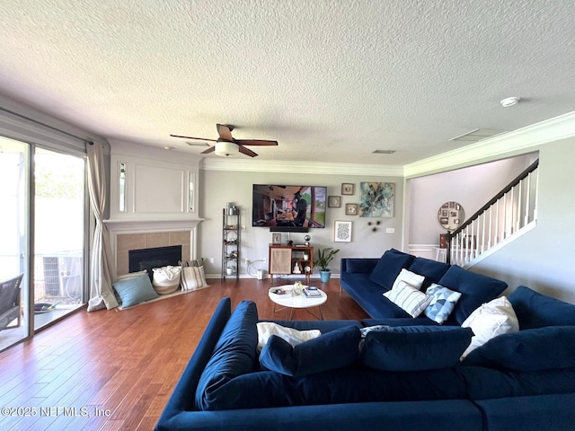 11110 Castlemain Cir S, Jacksonville, FL 32256 - living area with a textured ceiling, a tiled fireplace, wood finished floors, stairs, and ceiling fan