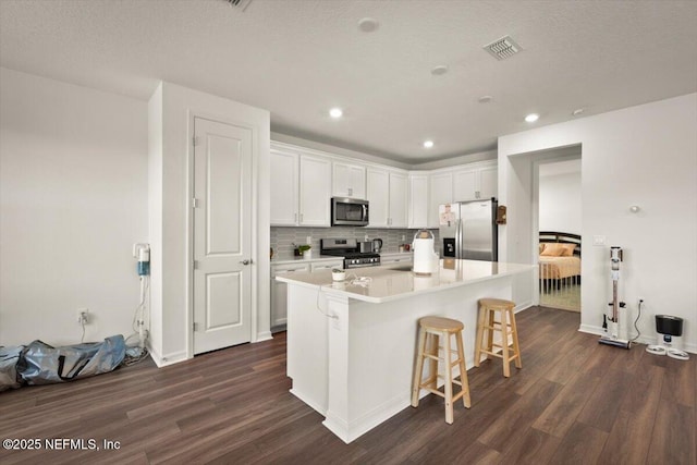 54 Torres Trce, Saint Augustine, FL 32095 - kitchen featuring stainless steel appliances, dark wood finished floors, white cabinets, a breakfast bar, and tasteful backsplash