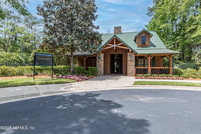 1804 Eagle Crest Dr, Fleming Island, FL 32003 - view of front facade with stone siding, a chimney, a porch, a standing seam roof, and a metal roof