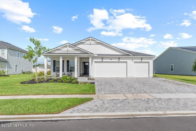 87 Tradesman Ln, Saint Johns, FL 32259 - view of front of home featuring a porch, decorative driveway, an attached garage, board and batten siding, and a front lawn