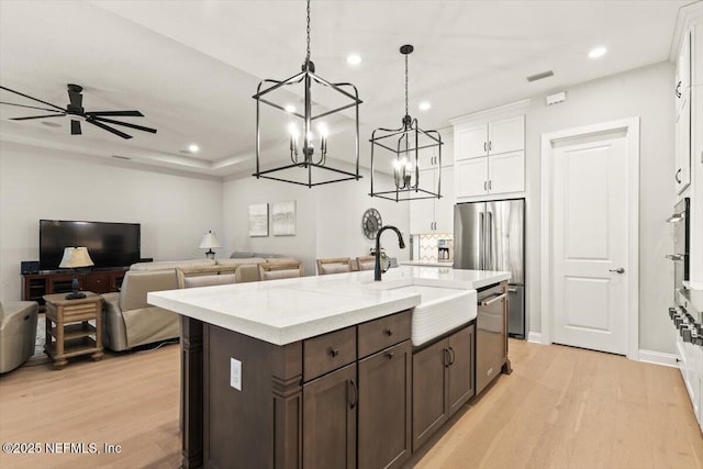 87 Tradesman Ln, Saint Johns, FL 32259 - kitchen featuring stainless steel appliances, white cabinets, light wood-style flooring, dark brown cabinets, and a chandelier