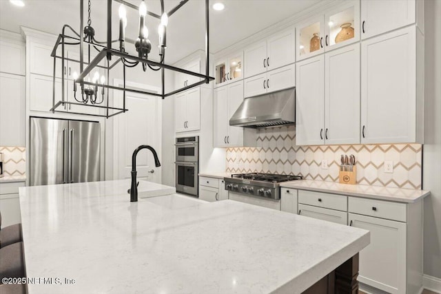 87 Tradesman Ln, Saint Johns, FL 32259 - kitchen featuring stainless steel appliances, under cabinet range hood, a chandelier, decorative backsplash, and light stone counters