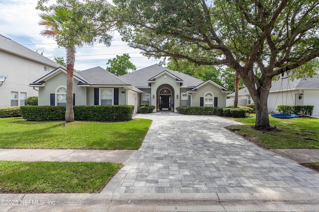7677 Crosstree Ln, Jacksonville, FL 32256 - ranch-style house featuring decorative driveway, a garage, stucco siding, and a front lawn