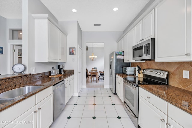 6542 Burnham Cir, Ponte Vedra Beach, FL 32082 - kitchen with stainless steel appliances, white cabinets, tasteful backsplash, baseboards, and dark stone counters