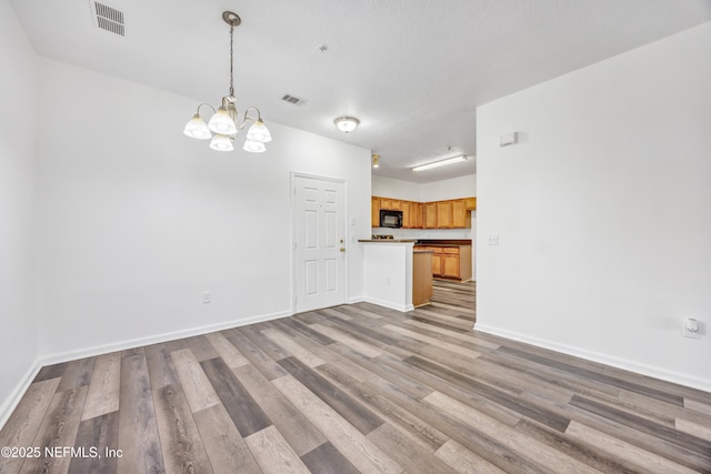 3641 Kirkpatrick Cir Unit 14-2, Jacksonville, FL 32210 - unfurnished living room with a chandelier, light wood-type flooring, and baseboards