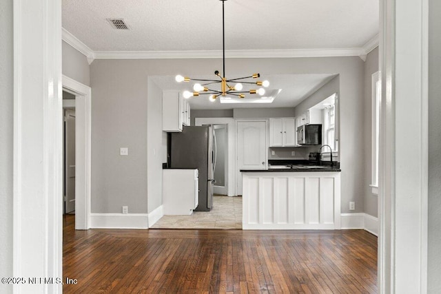 1032 Ingleside Ave, Jacksonville, FL 32205 - kitchen featuring stainless steel appliances, a chandelier, white cabinets, hardwood / wood-style flooring, and dark countertops