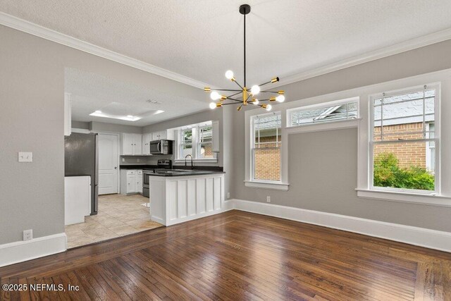 1032 Ingleside Ave, Jacksonville, FL 32205 - kitchen with appliances with stainless steel finishes, a chandelier, crown molding, dark countertops, and a peninsula