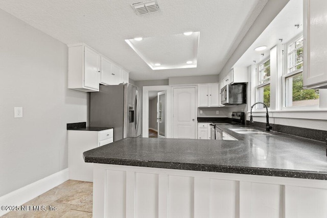 1032 Ingleside Ave, Jacksonville, FL 32205 - kitchen with appliances with stainless steel finishes, white cabinetry, dark countertops, a textured ceiling, and a peninsula