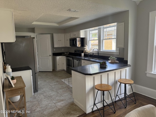 1032 Ingleside Ave, Jacksonville, FL 32205 - kitchen with stainless steel appliances, a peninsula, dark countertops, a kitchen breakfast bar, and white cabinetry