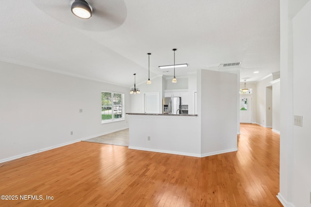 2002 Knottingham Trace Ln, Jacksonville, FL 32246 - unfurnished living room featuring light wood-style flooring, crown molding, vaulted ceiling, ceiling fan, and a chandelier
