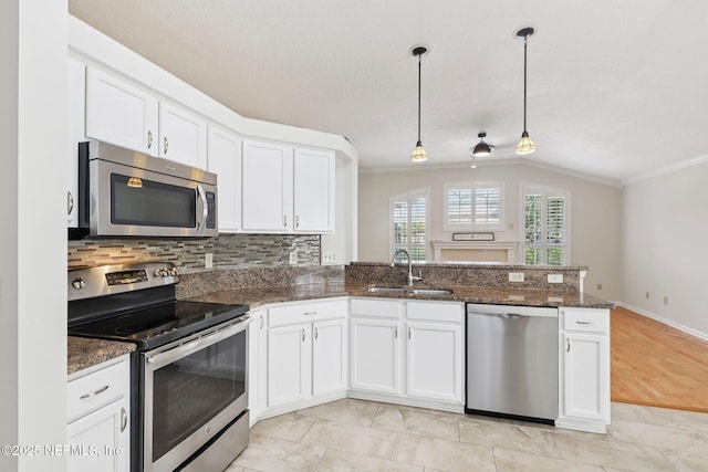 2002 Knottingham Trace Ln, Jacksonville, FL 32246 - kitchen with appliances with stainless steel finishes, ornamental molding, a peninsula, white cabinetry, and dark stone counters