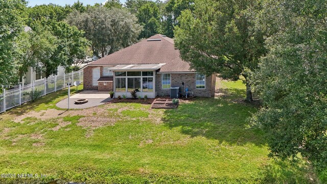 2002 Knottingham Trace Ln, Jacksonville, FL 32246 - rear view of property featuring a sunroom, a fire pit, a patio area, brick siding, and roof with shingles