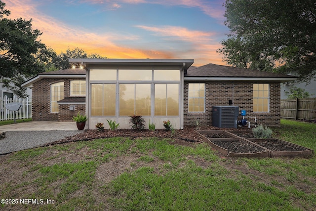 2002 Knottingham Trace Ln, Jacksonville, FL 32246 - back of property featuring a vegetable garden, brick siding, a sunroom, and a patio area