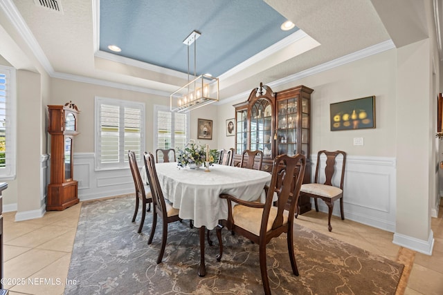 2144 S Sorrento Hills Rd, Saint Augustine, FL 32092 - dining area with a raised ceiling, crown molding, light tile patterned floors, a decorative wall, and a wainscoted wall