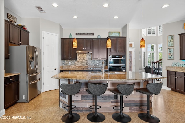 2148 S Sorrento Hills Rd, Saint Augustine, FL 32092 - kitchen with stainless steel appliances, light stone counters, dark brown cabinetry, and recessed lighting
