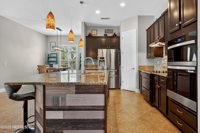 2148 S Sorrento Hills Rd, Saint Augustine, FL 32092 - kitchen with appliances with stainless steel finishes, dark brown cabinets, light stone countertops, a kitchen bar, and recessed lighting