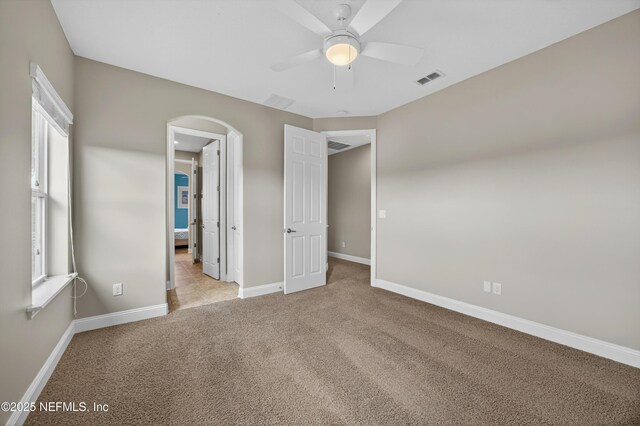 2148 S Sorrento Hills Rd, Saint Augustine, FL 32092 - unfurnished bedroom featuring carpet floors, arched walkways, a ceiling fan, and ensuite bathroom